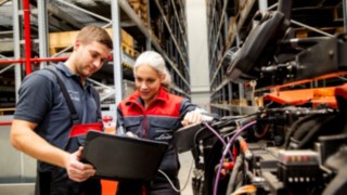 A Linde Anyagmozgatás két szerviztechnikusa egy laptopot néz egy targonca mellett állva.