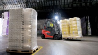 H20 típusú gázüzemű targonca – az új generáció A Linde emelővillás targoncája világítás segítségével szállít árut egy sötét csarnokban