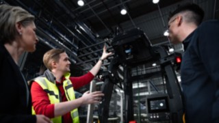 Hárman állnak a Linde MH egy automatizált targoncája előtt.
