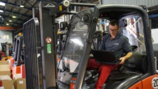 Technikus ellenőriz egy használt targoncát Technikus laptop számítógéppel egy targonca felújítás előtti ellenőrzésénél