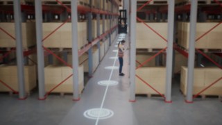 Szűkfolyosós raktárban tartózkodó védőmellényes alkalmazottat és a személyfelismerő rendszer biztonsági zónáit ismertető animáció