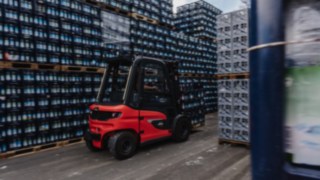 Testre szabott biztonsági megoldást kínálunk a vállalata intralogisztikai rendszeréhez. A Linde X30 sorozatú elektromos targoncája italosládákat szállít egy külső raktár szűk folyosóján.