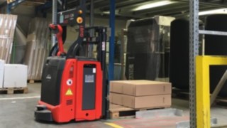 A Linde L-MATIC sorozatú járműve a helyi komissiózócsapatot támogatja. A Linde L-MATIC sorozatú járműve egy csomagokkal teli raklapot helyez a polcra.