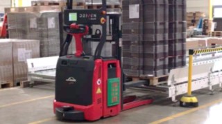 A Linde L-MATIC sorozatú járműve teljesen önállóan ismeri fel az árut és helyezi a szállítóberendezésre. A Linde L-MATIC sorozatú targoncája szállítószalagra helyez egy raklapot.
