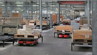 A Linde MH C-MATIC automatizált platformjárművei ládákat és raklapokat szállítanak az ABS Safety raktárában,