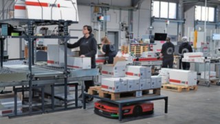 A Linde MH C-MATIC automatizált platformjárműve az ABS Safety raktári dolgozóinak csoportja között.