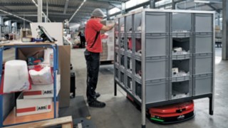 Az ABS Safety egyik munkatársa egy polcról veszi le az alkatrészeket, amelyeket a Linde MH C-MATIC járműve szállított oda neki.