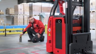A Linde MH munkatársa egy L-MATIC előtt térdel, és ellenőrzi, hogy minden rendben van-e.