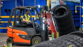 A Michelin Tyre PLC munkatársa egy gumiabroncsrakat után nyúl a targoncára szerelt fogóval.
