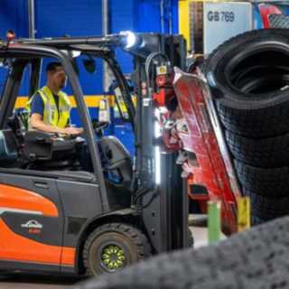 A Michelin Tyre PLC munkatársa egy gumiabroncsrakat után nyúl a targoncára szerelt fogóval.