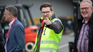 eMission ZERO: A Linde Anyagmozgatás saját hidrogén-infrastruktúrát üzemeltet Egy láthatósági mellényt viselő férfi a kamerába néz és mutat