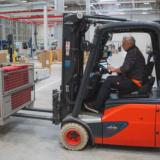 Egy Linde elektromos targonca rácsos ládát szállít