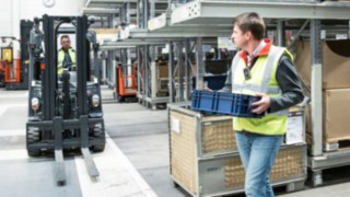 Munkavállalók viselik a Linde Safety Guard eszközt a raktárban.