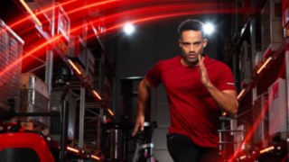 Egy sportoló fut egy raktárban, a háttérben a Linde Anyagmozgatás Ri16 sorozatú tolóoszlopos targonca látható.