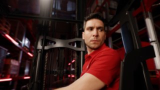 Közelkép az Ri16 sorozatú tolóoszlopos targonca ergonomikus vezetőfülkéjében ülő vezetőről.