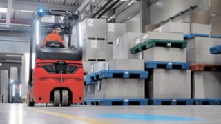 Legyen szó előre- vagy hátramenetről: Az ergonomikus fülke minimálisra csökkenti a vezetőre háruló fizikai megterhelést. Egy targoncavezető tolat a raktárban a Linde elektromos targoncájával.