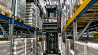 A Linde K-MATIC automatizált szűkfolyosós targoncája áthalad egy állványfolyosón közlekedik.